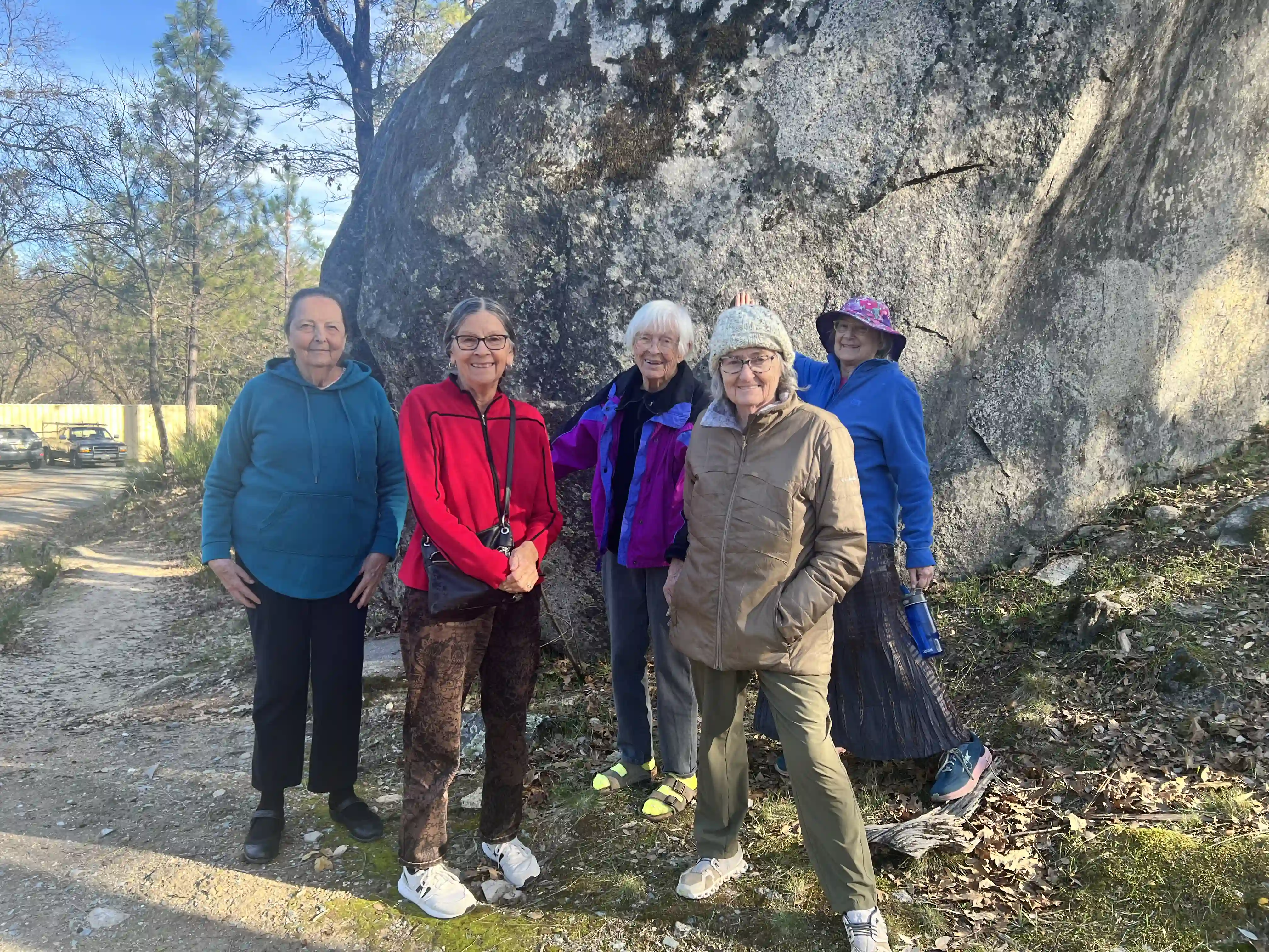 Five elderly padies standing in front of a large boulder.