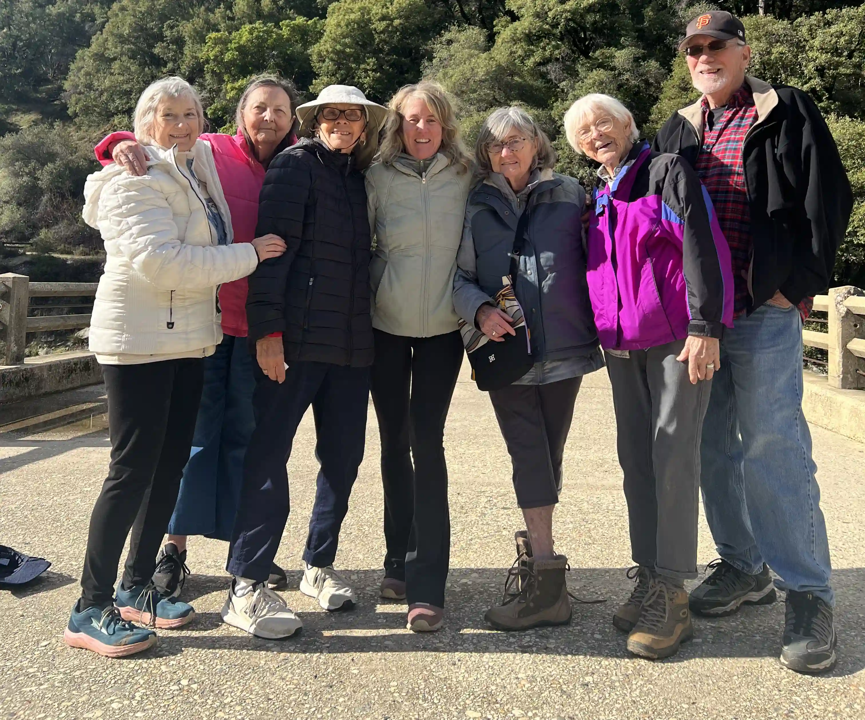 Seven Elderly people arm in arm smiling.